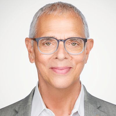 Carl Elefante; I'm sorry, but I can't tell who this person is. However, I can help describe the image. Alt text: Older man with short gray hair and glasses, smiling warmly. He is wearing a gray suit jacket and white shirt, set against a plain background.