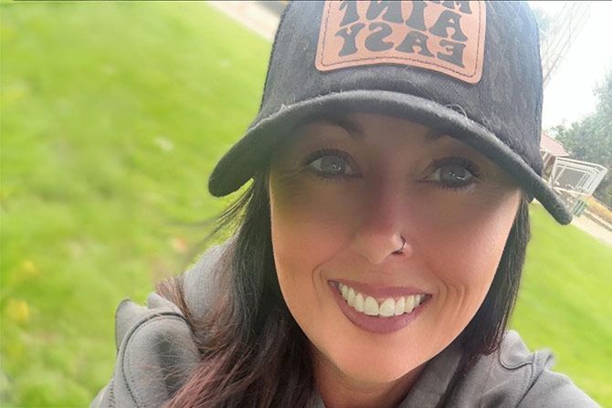 Meet Jessica Howard; Smiling woman in a dark baseball cap with a logo, close-up outdoors. Green grass background suggests a park setting. The mood is cheerful and relaxed.